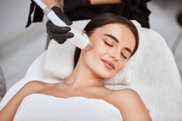 Beautiful Girl Lying In Spa Salon Covering Breast With White Towel And Getting Massage For Her Cheek With Professional Apparat  Laser Hair Removal Stock Pictures, Royalty-Free Photos &Amp; Images